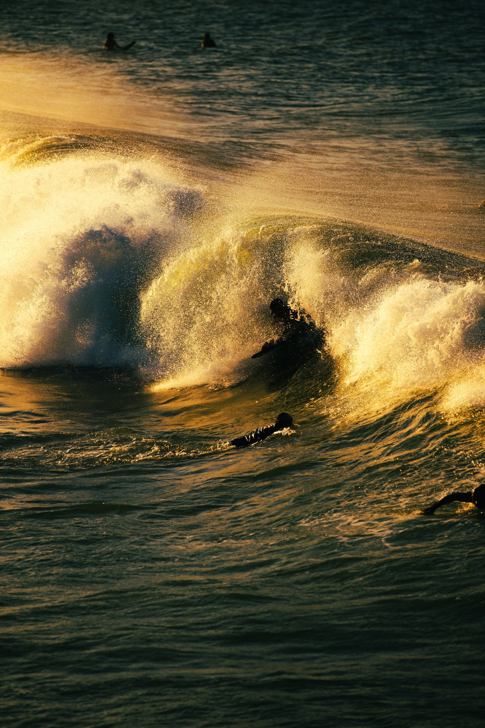 A surfer riding a wave at sunrise